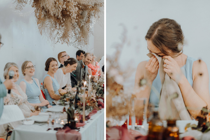 Top table laugh during wedding speech and bridesmaid cries and wipes tear with napkin