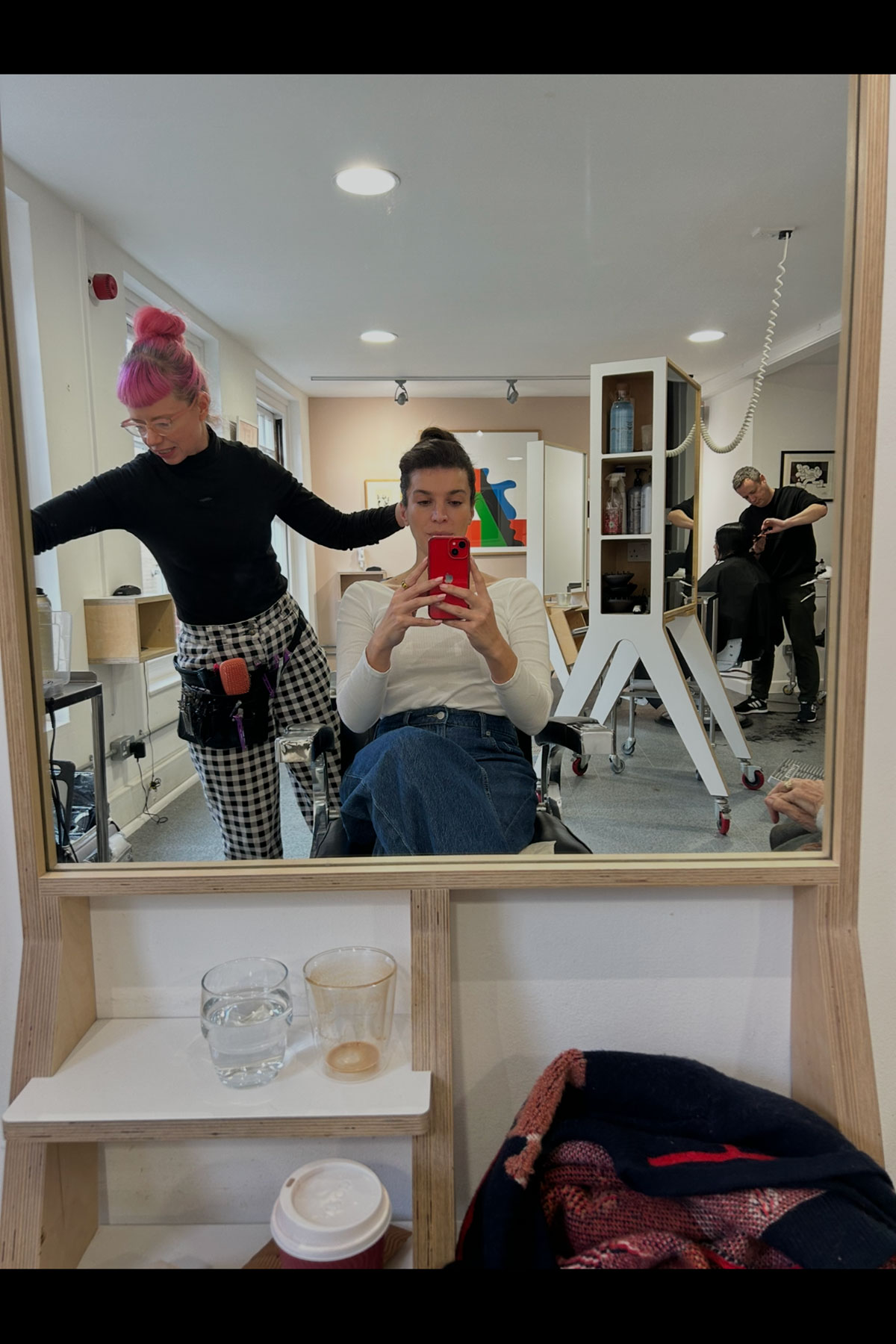 Bride having hair styled in salon while taking mirror selfie during wedding morning prep