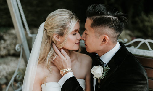 a bride and groom posing nose-to-nose for a wedding photo