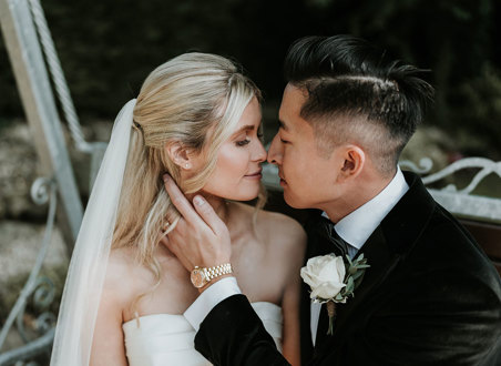a bride and groom posing nose-to-nose for a wedding photo