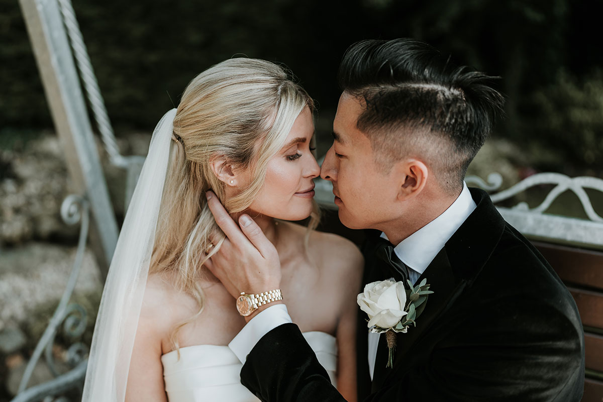 a bride and groom posing nose-to-nose for a wedding photo