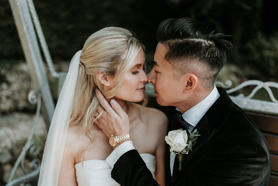 a bride and groom posing nose-to-nose for a wedding photo