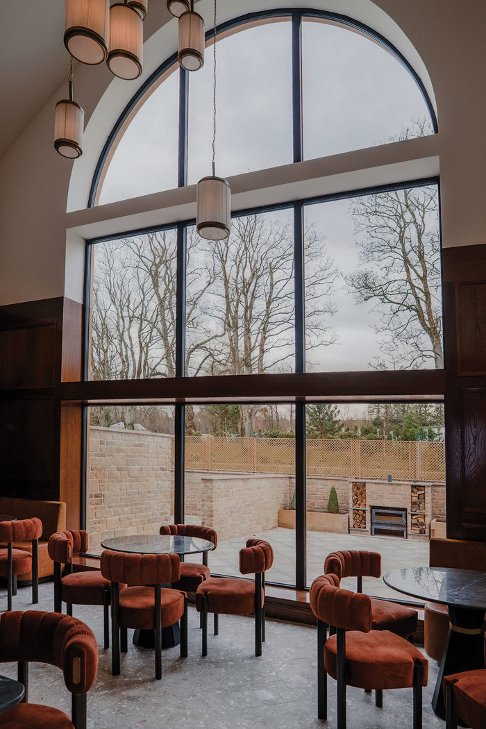 Trocadero's terrace at Crossbasket Castle with burnt orange furnishings and floor to ceiling windows