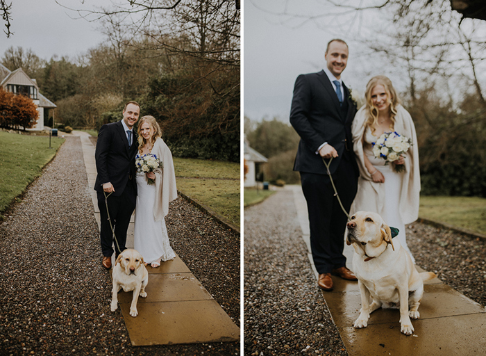 A bride and groom stand on a path with a yellow Labrador on a lead