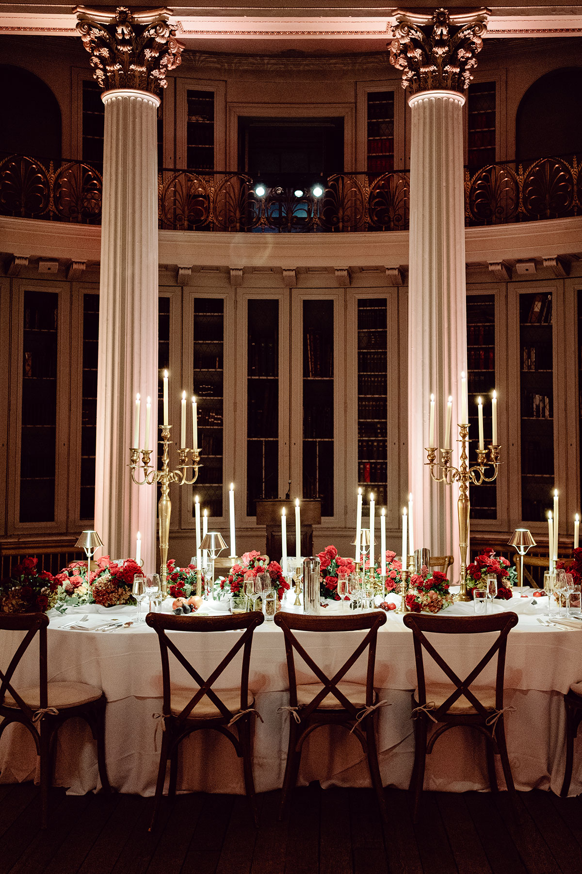 Elegant banquet table surrounded by wooden chairs, tall columns and bookshelves inside the Signet Library’s historic reception space