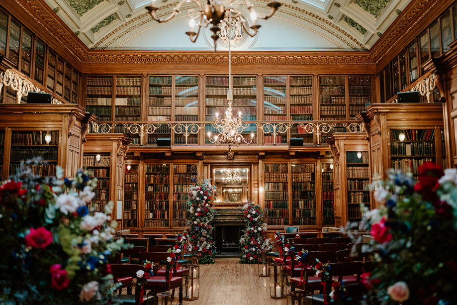 Grand hall with beautiful floral displays and chairs set up for a wedding ceremony