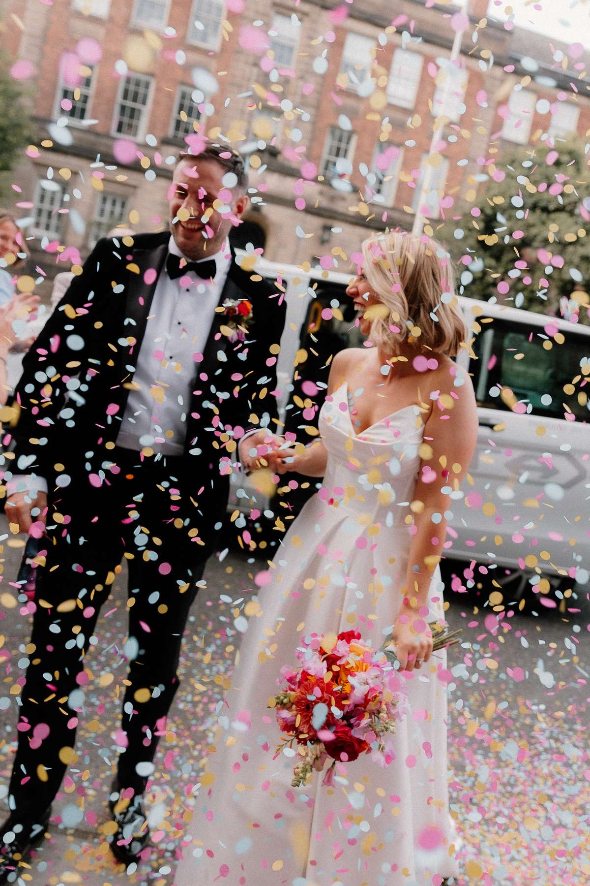 Kara and Rory laugh beneath a shower of colourful confetti as they arrive for their wedding reception in Leith.