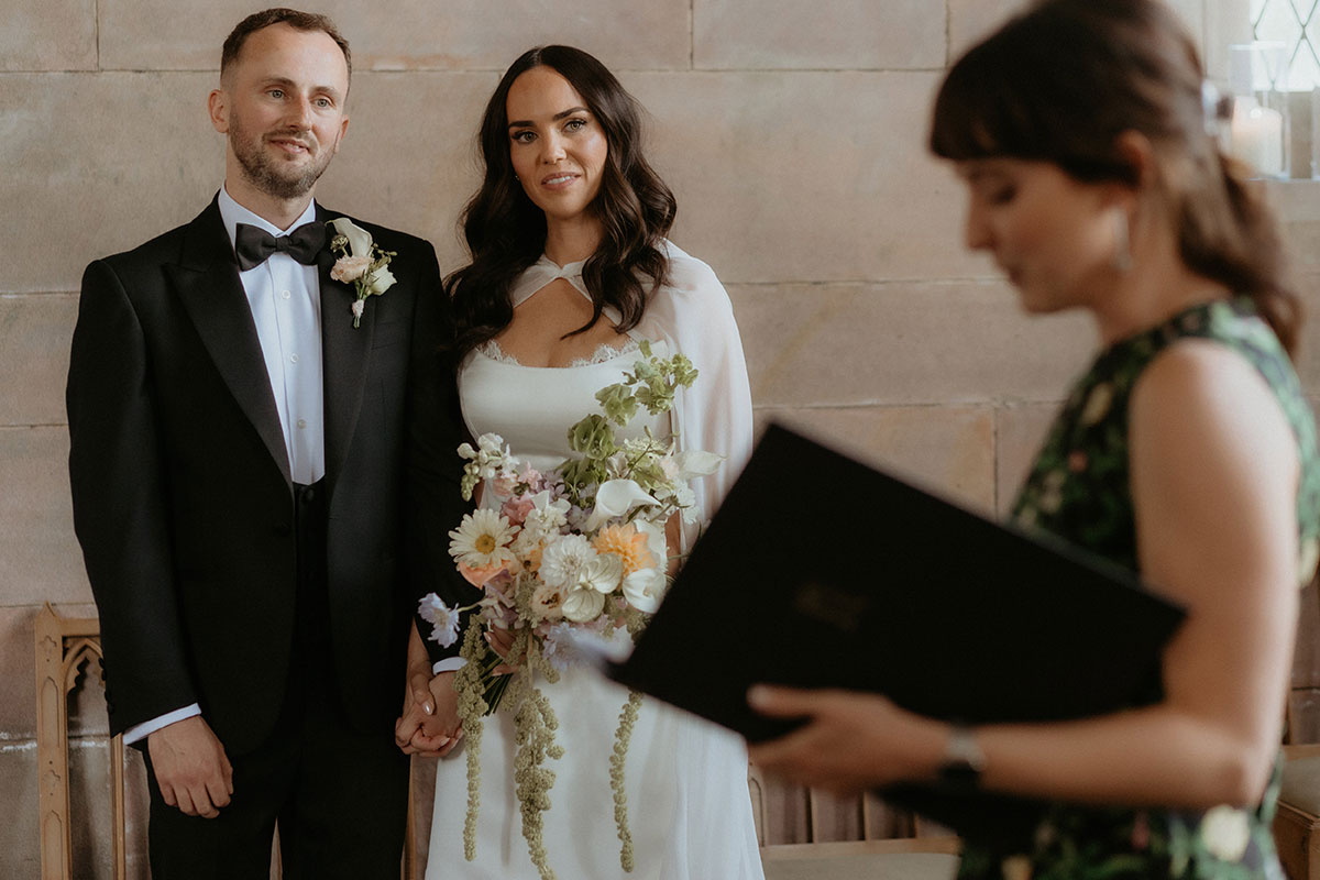 Bride and groom holding hands during wedding ceremony at Rosebery House and Steading, Midlothian.