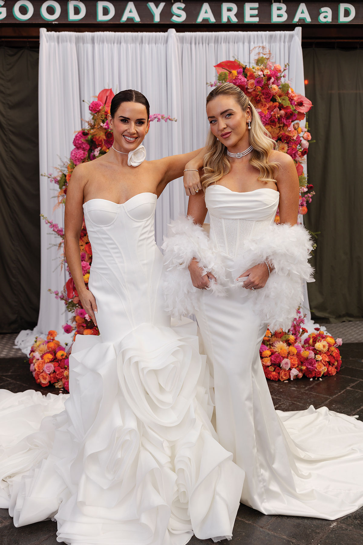 Modern bridal models in structured white gowns at colourful floral backdrop at BAaD Glasgow