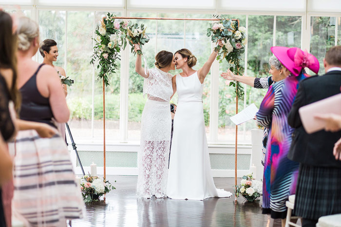 two brides kiss during their wedding ceremony