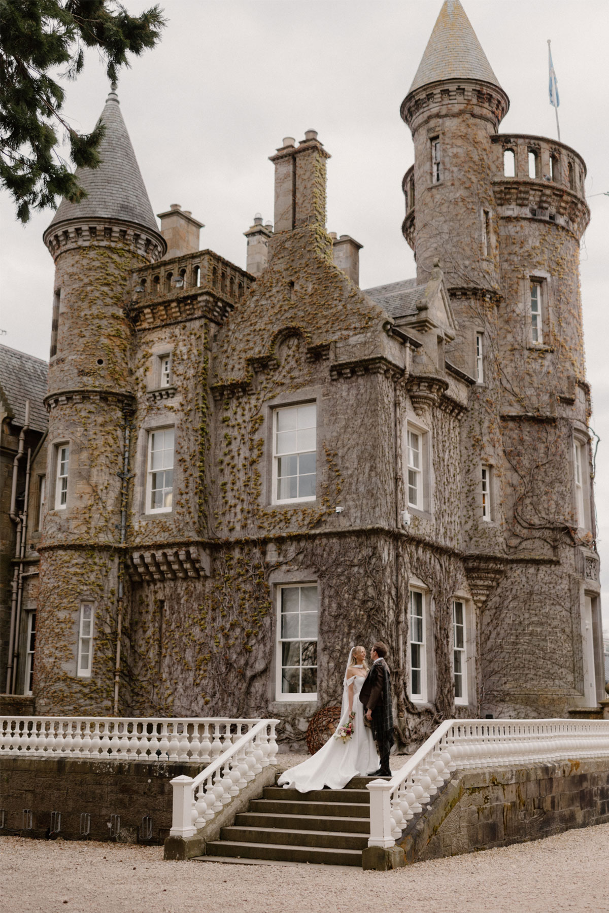 a bride and groom look into each other's eyes while standing in front of a castle