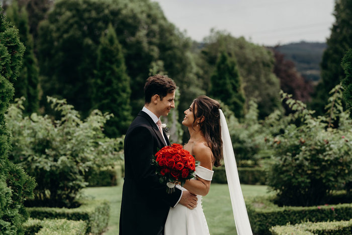 a bride and groom posing for a photo in a green garden setting at Achnagairn Castle