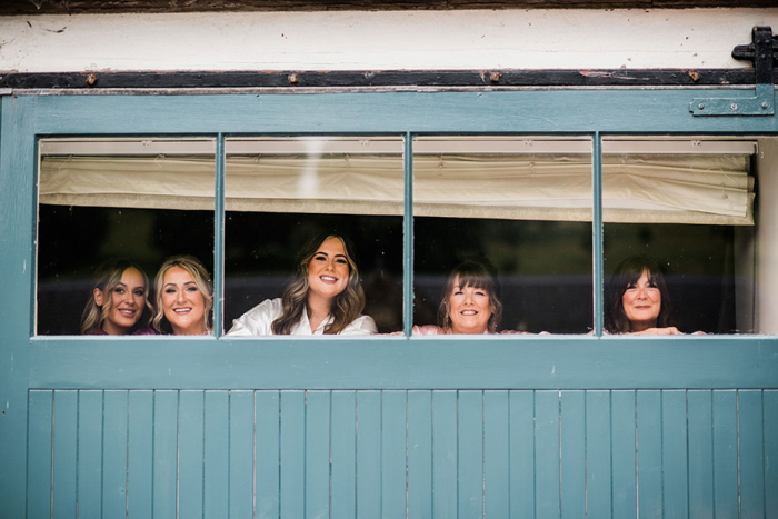 Bridal party smile from windows at the wedding venue