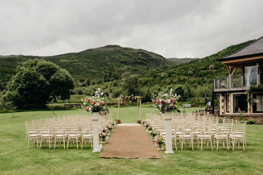 an outdoor wedding ceremony facing a large hill and trees