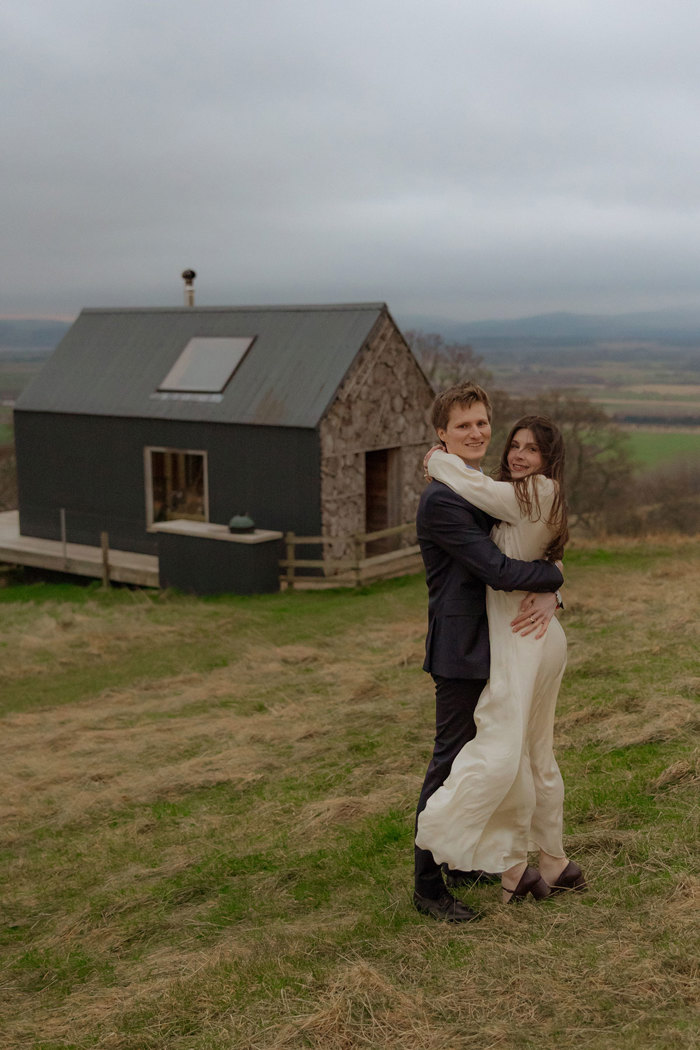 bride and groom hug while standing on grass at guardswell farm