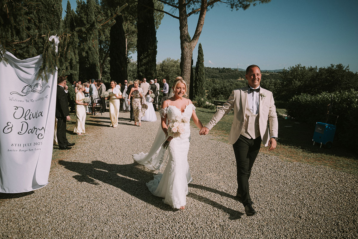 Newlyweds walking hand in hand after outdoor Tuscany wedding ceremony at Antico Borgo San Lorenzo