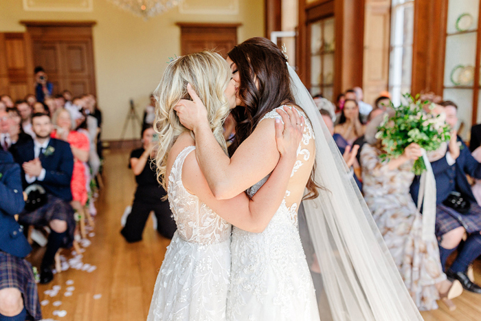 Brides kiss during their ceremony