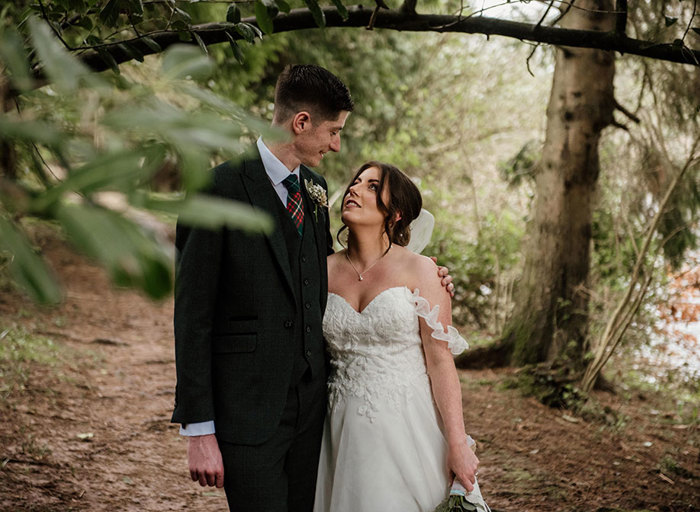 bride and groom looking at each other in a woodland