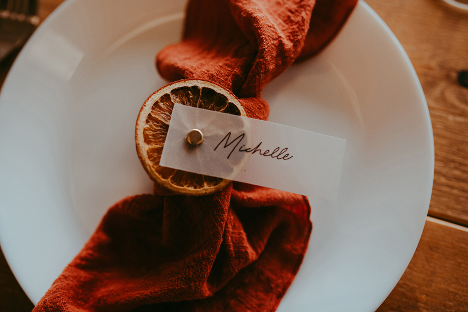 Guest's name card attached to dried orange and orange fabric set on top of their plate