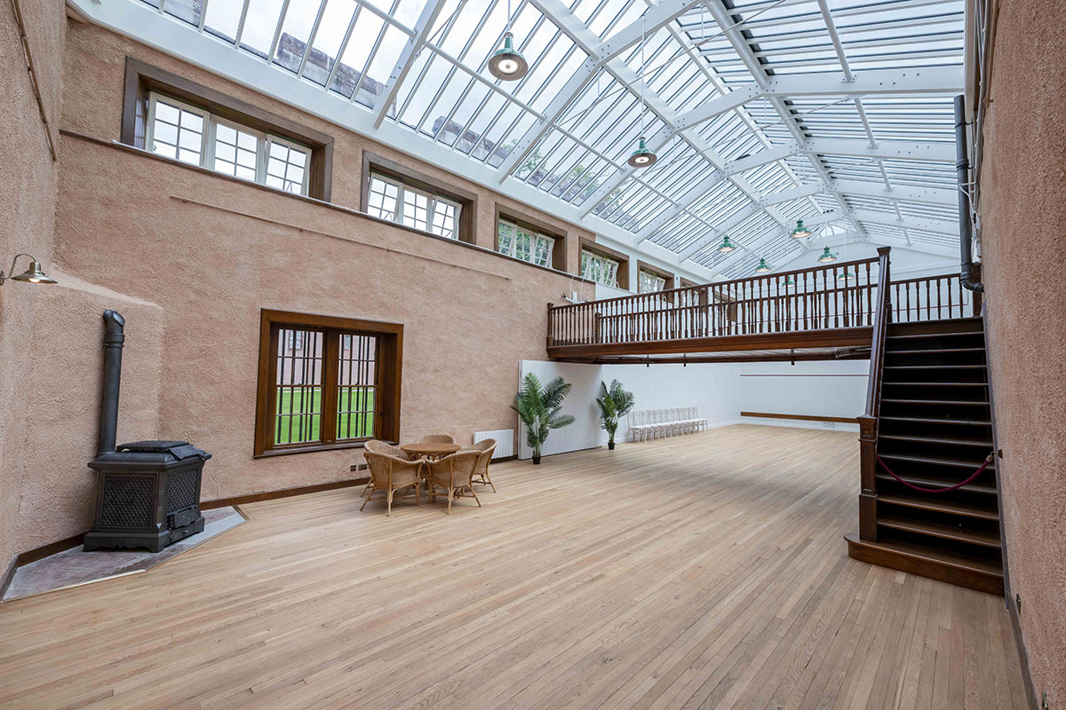 Restored Racquets Court wedding reception space at Fyvie Castle with glazed roof, wooden floor and viewing balcony