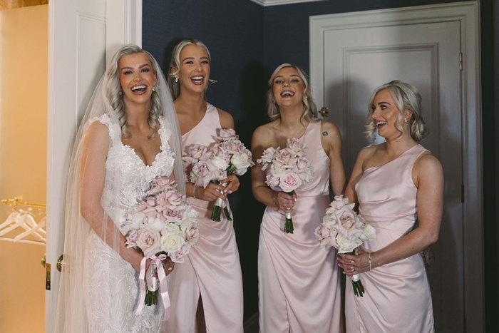 Bride laughs with three of her bridesmaids who are wearing pink gowns