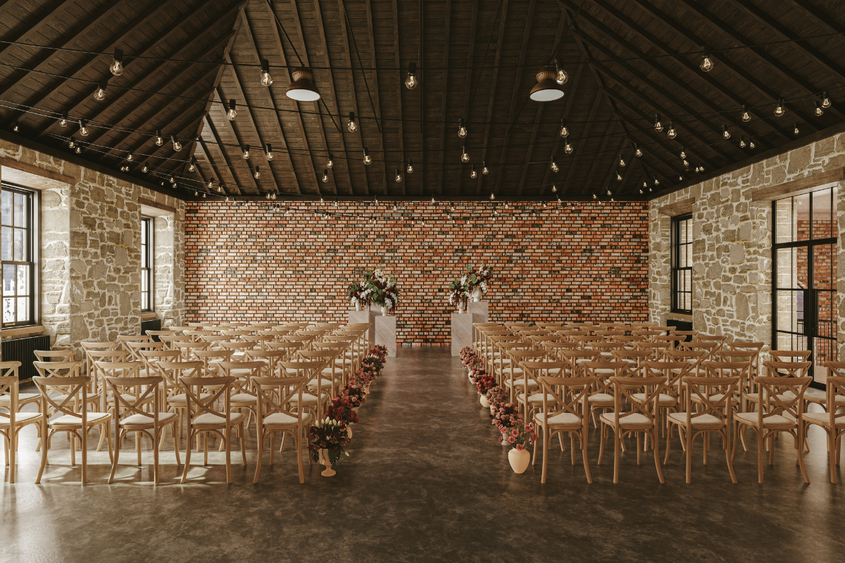 Gallery Room at The West Works Glasgow set for a wedding ceremony with wooden chairs, floral aisle decor and festoon lighting
