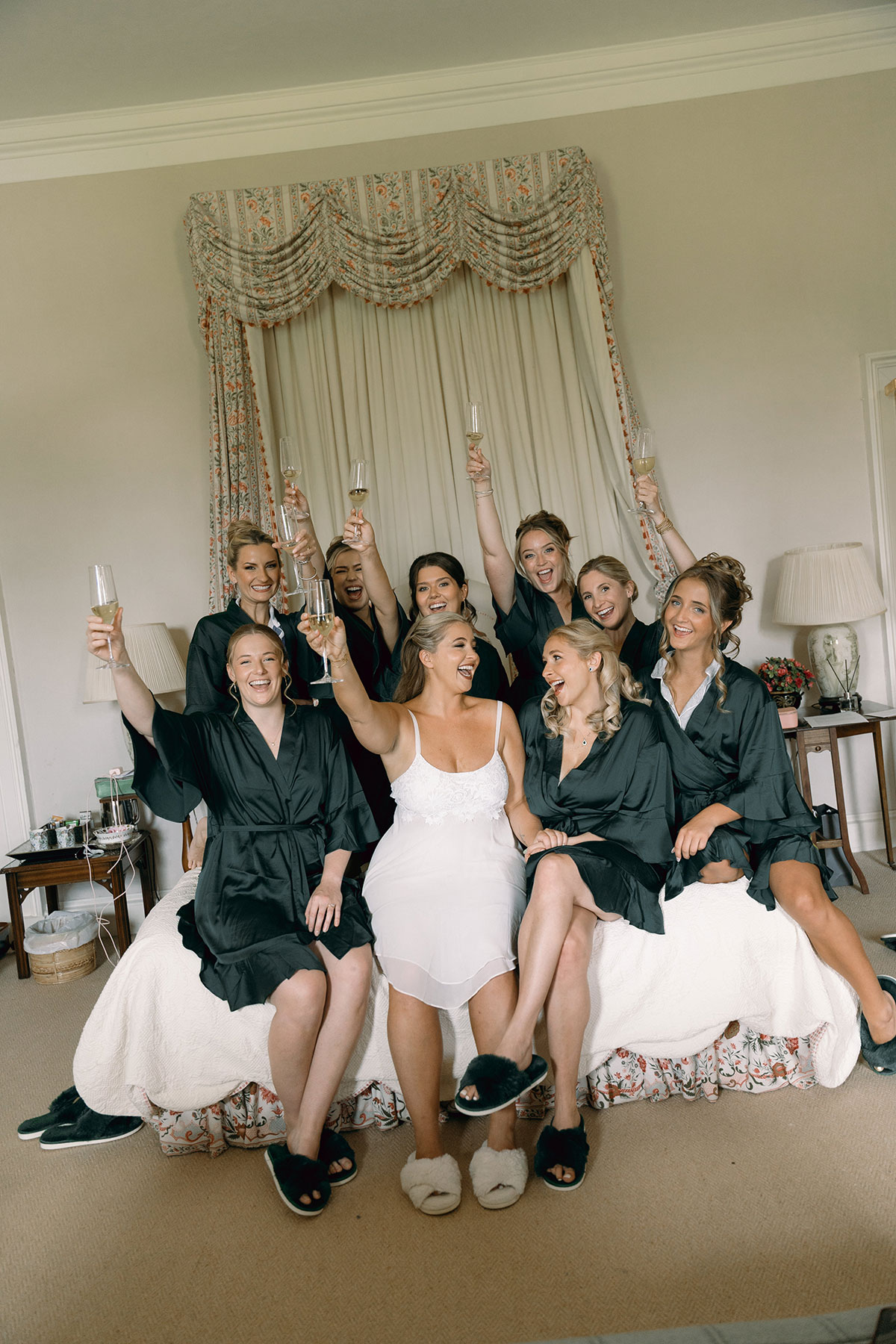 Bride and bridesmaids in matching robes celebrate with champagne on the morning of the Dundas Castle wedding.