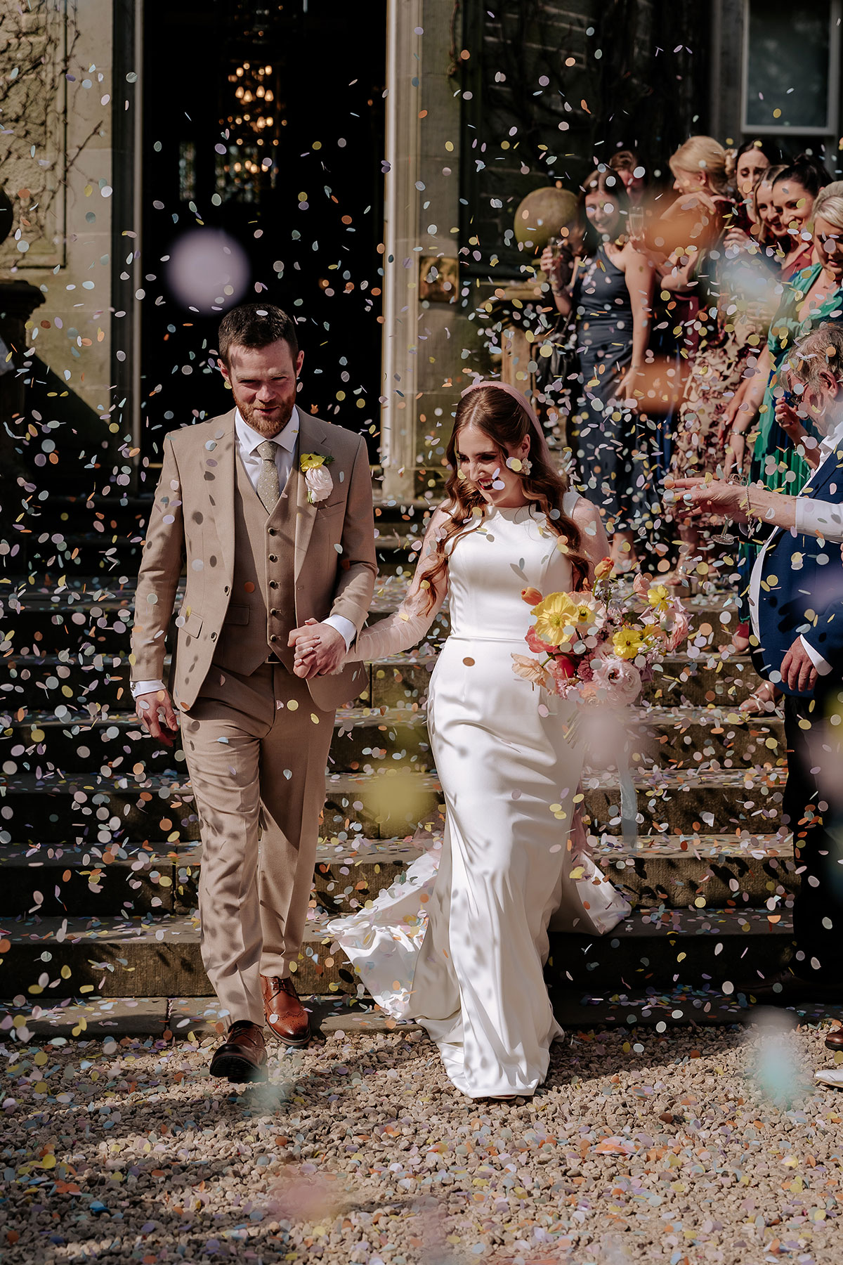 a bride and groom being showered in confetti outside Carlowrie Castle Edinburgh wedding venue