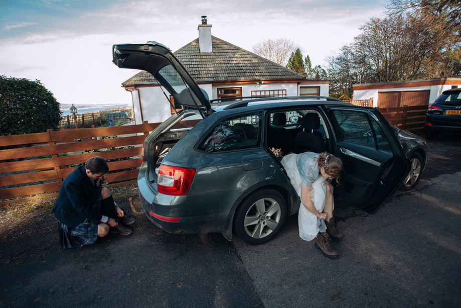 A car with bride and groom putting walking boots on