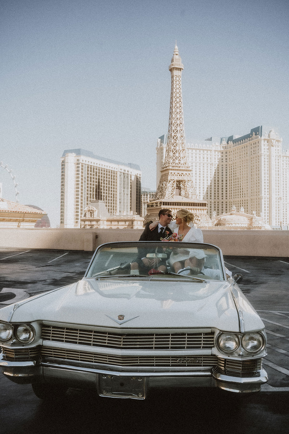 bride and groom kiss in vintage car with las vegas replica of the eiffel tower