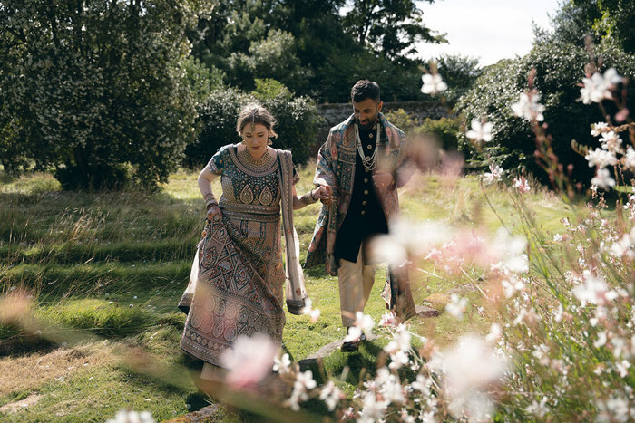 A bride and groom wearing Indian attire walking in the walled garden at Byre of Inchyra.