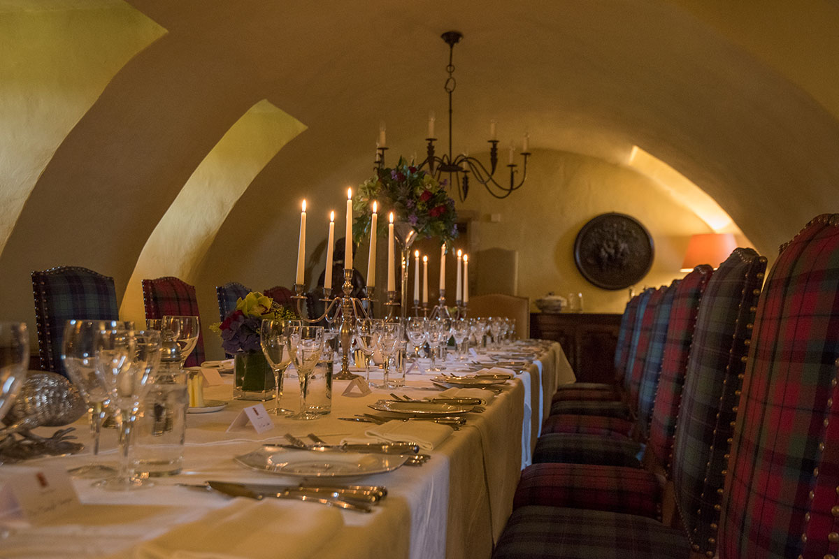 Candlelit wedding banquet set in a vaulted dining room at Fenton Tower