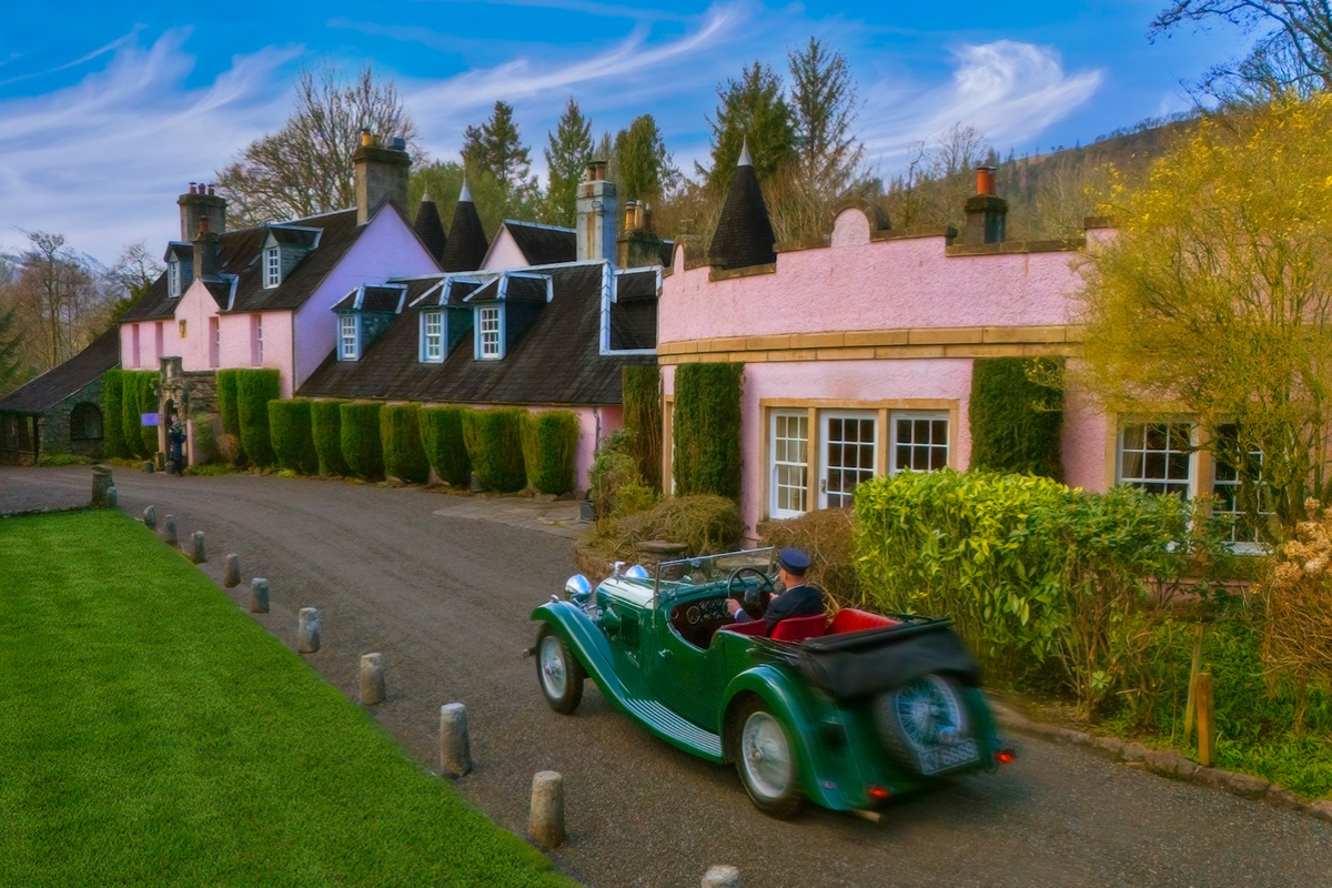 Vintage green car driving past the pink exterior of Thackray House wedding venue in Callander.