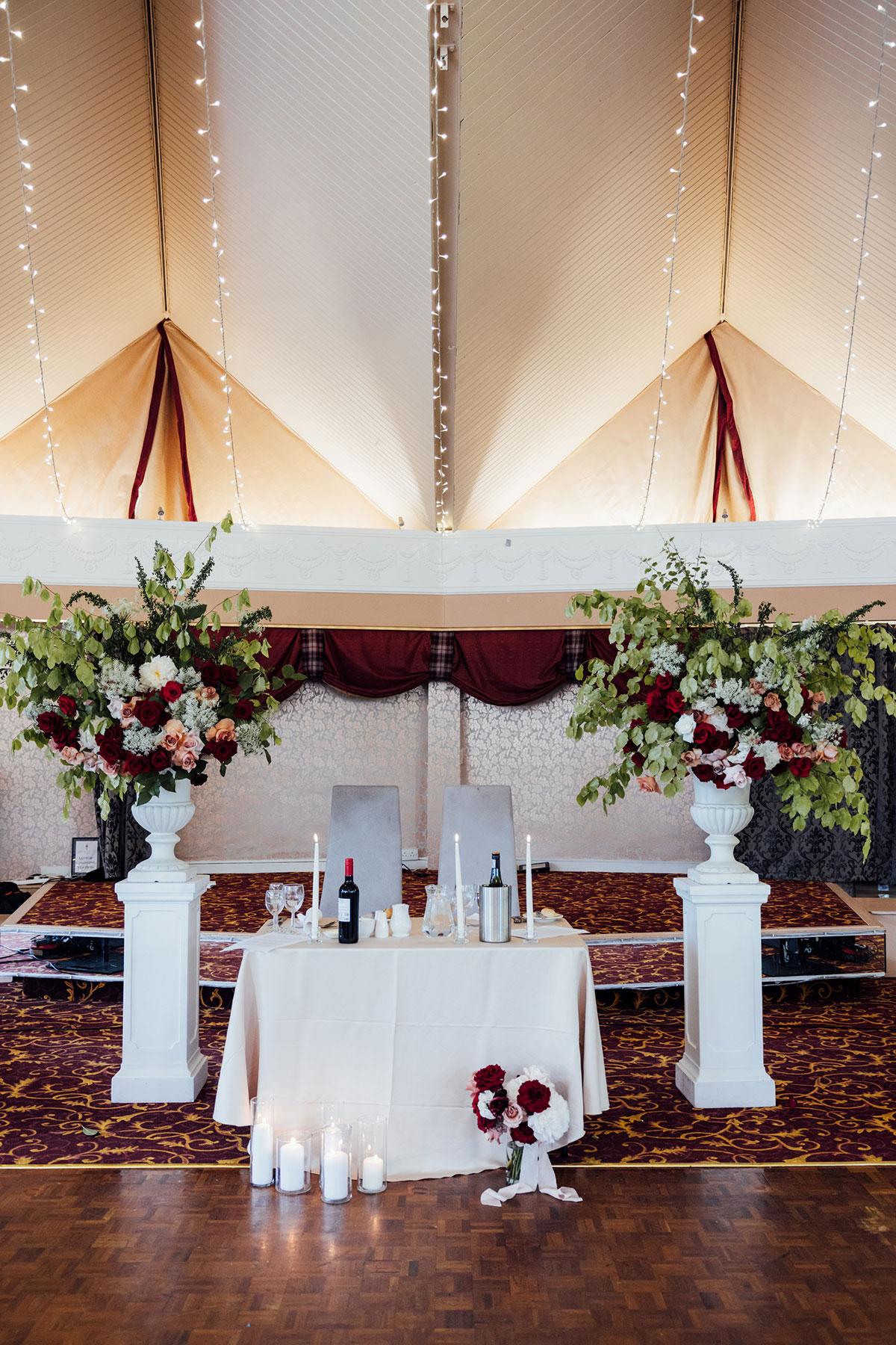 Wedding reception setup at Atholl Palace Hotel featuring floral ceremony pillars, fairy lights and the top table