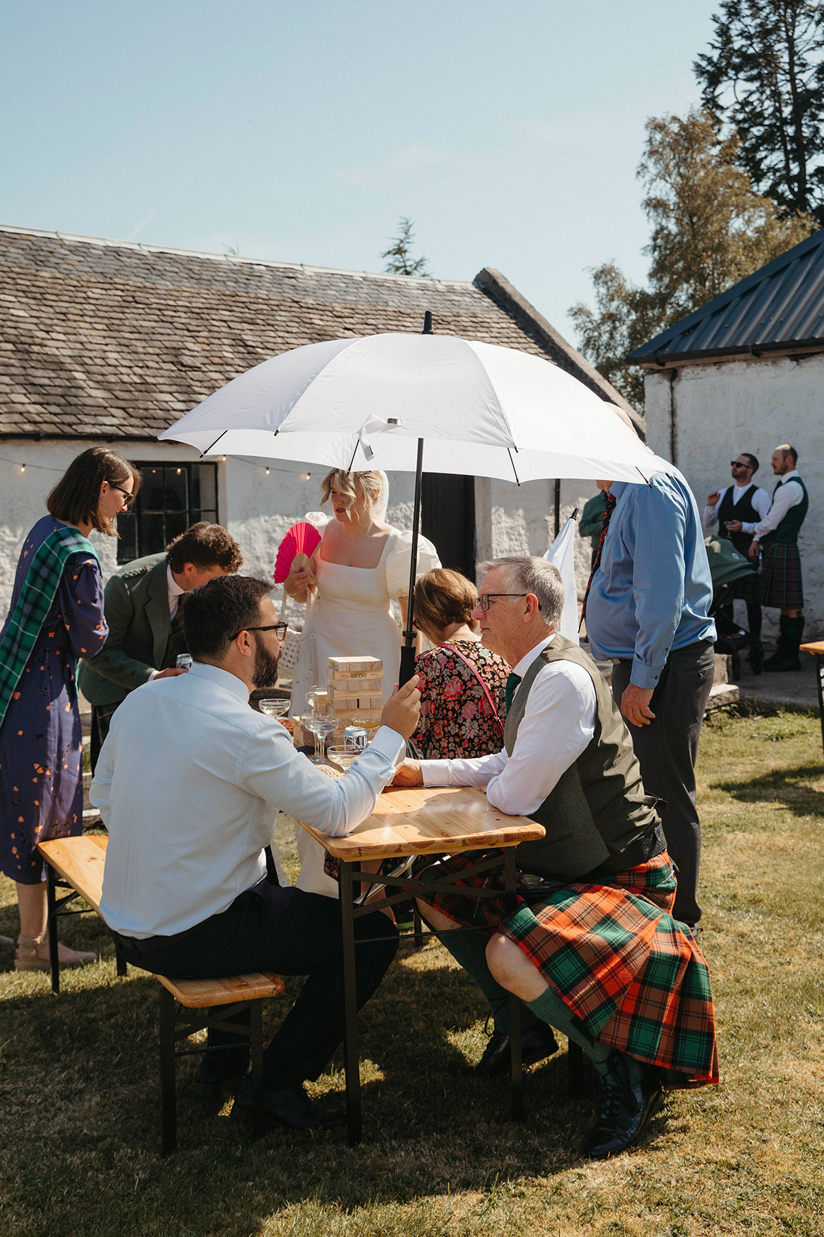 Guests gather for outdoor drinks reception during DIY Cairngorms farmhouse wedding celebration