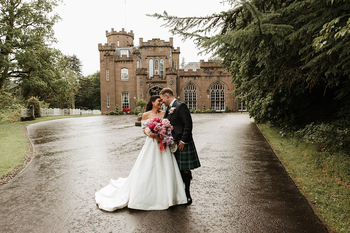 Bride and groom outside Drumtochty Castle Aberdeenshire wedding venue with bouquet and castle backdrop