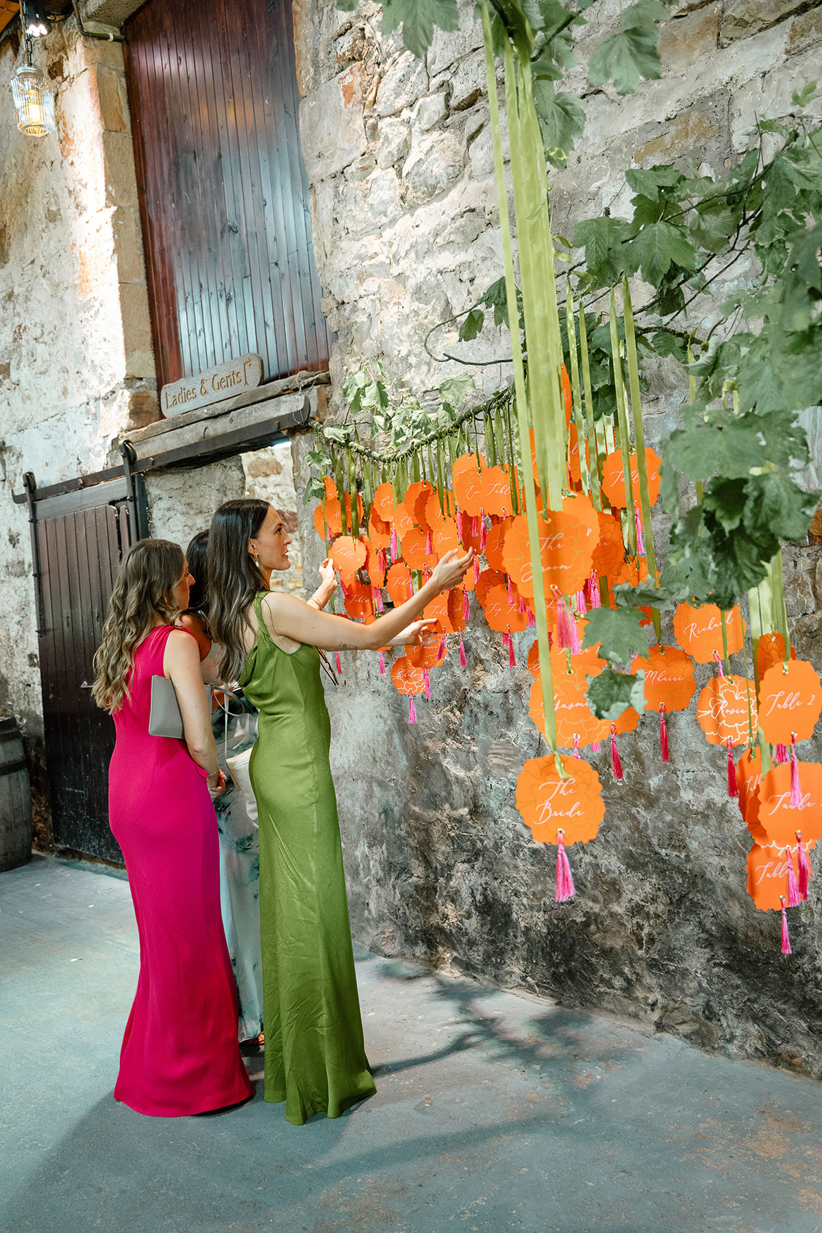 Guests with marigold paper flower interactive table plan at a Kinkell Byre wedding.
