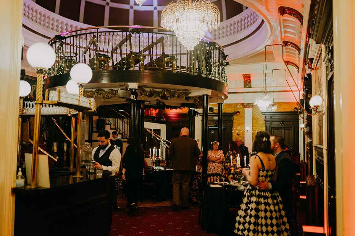 Wedding reception at The Savings Bank in Glasgow with chandeliers, balcony seating and guests gathered around candlelit tables