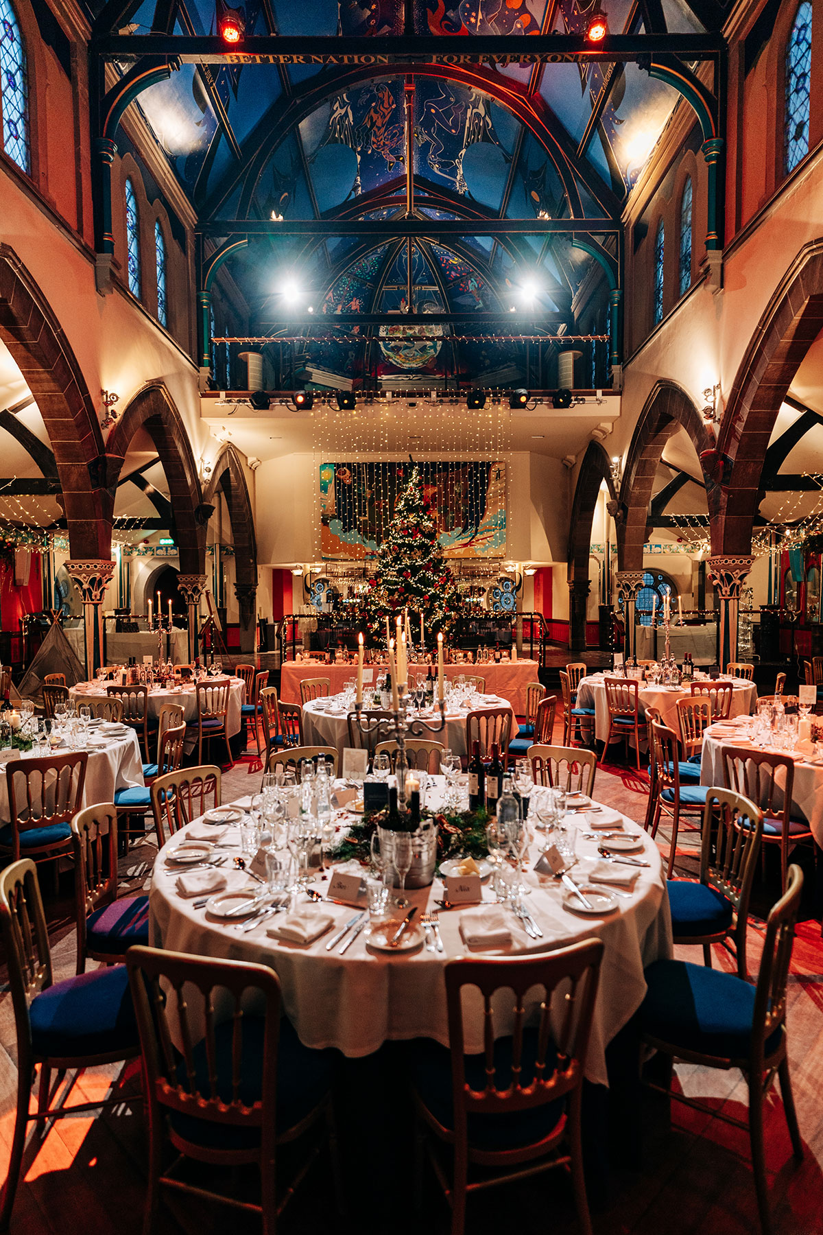 dinner set up for wedding at oran mor with round tables, fairy lights and christmas tree