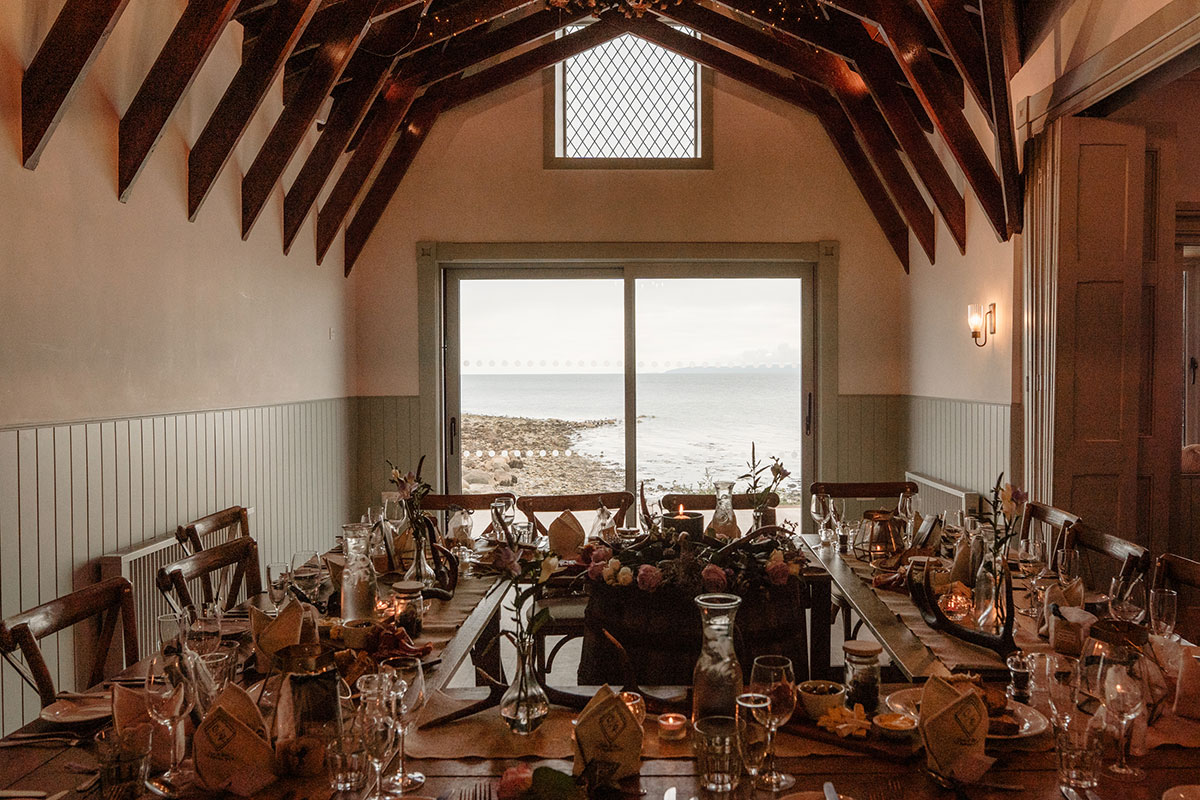 Wedding reception table inside The Dougarie Boathouse on Arran with sea views across the Kilbrannan Sound