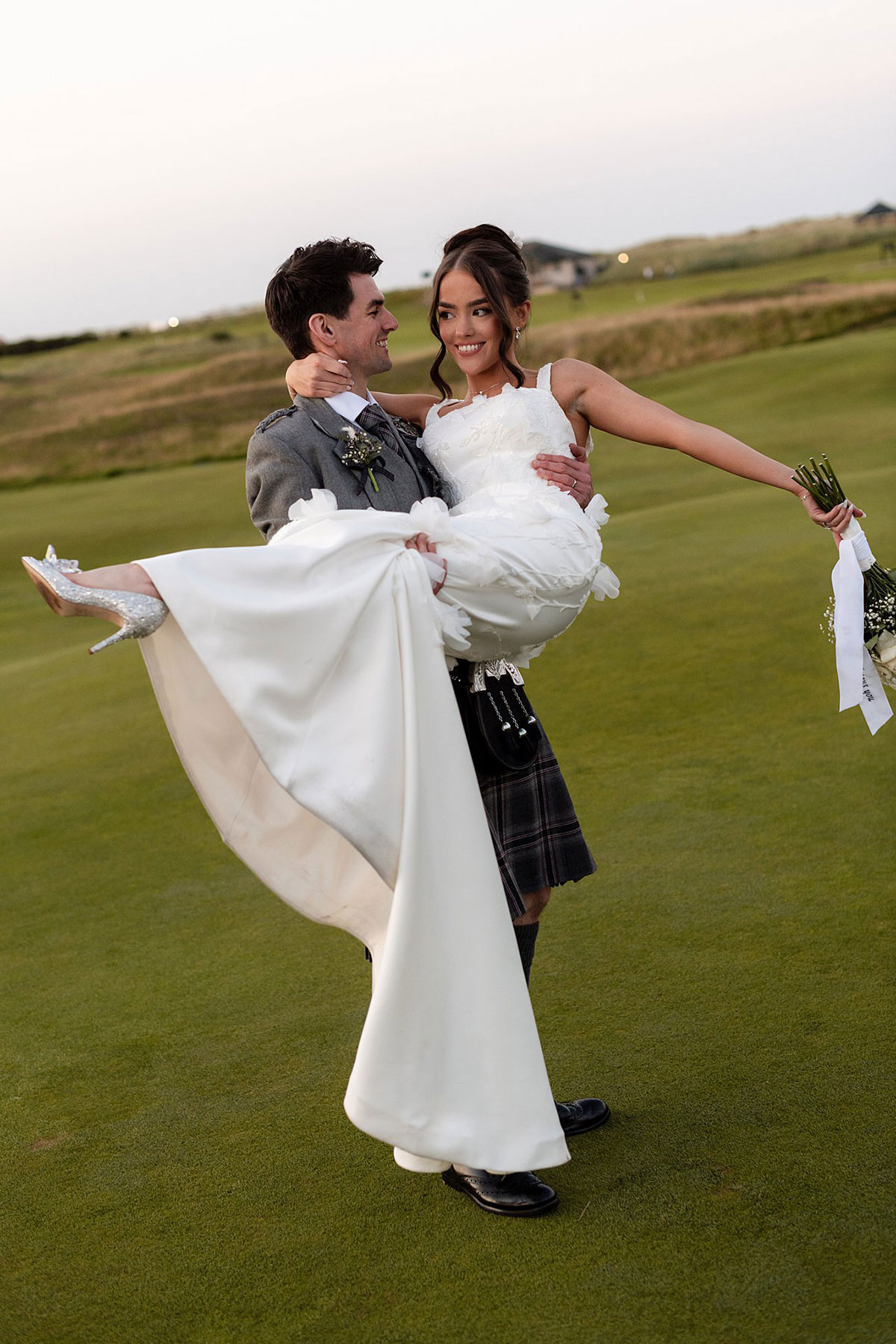 Groom lifting bride in wedding dress on the Old Course golf course during Old Course Hotel St Andrews wedding portraits.