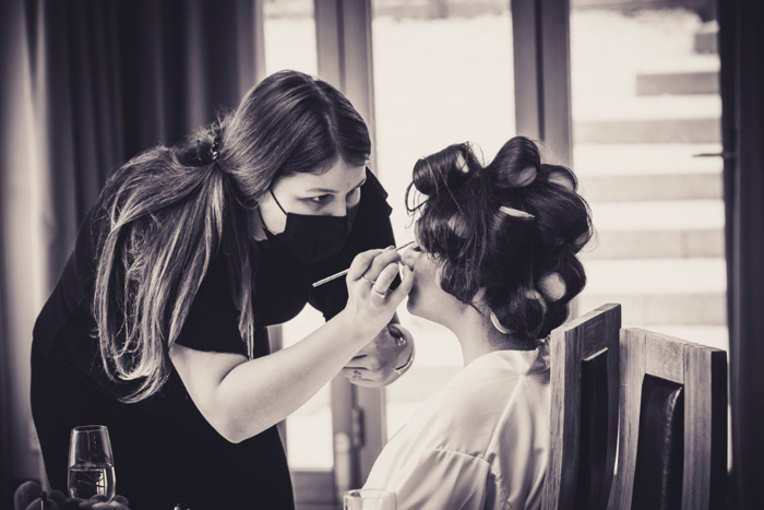 Black and white photo of bride getting her makeup done
