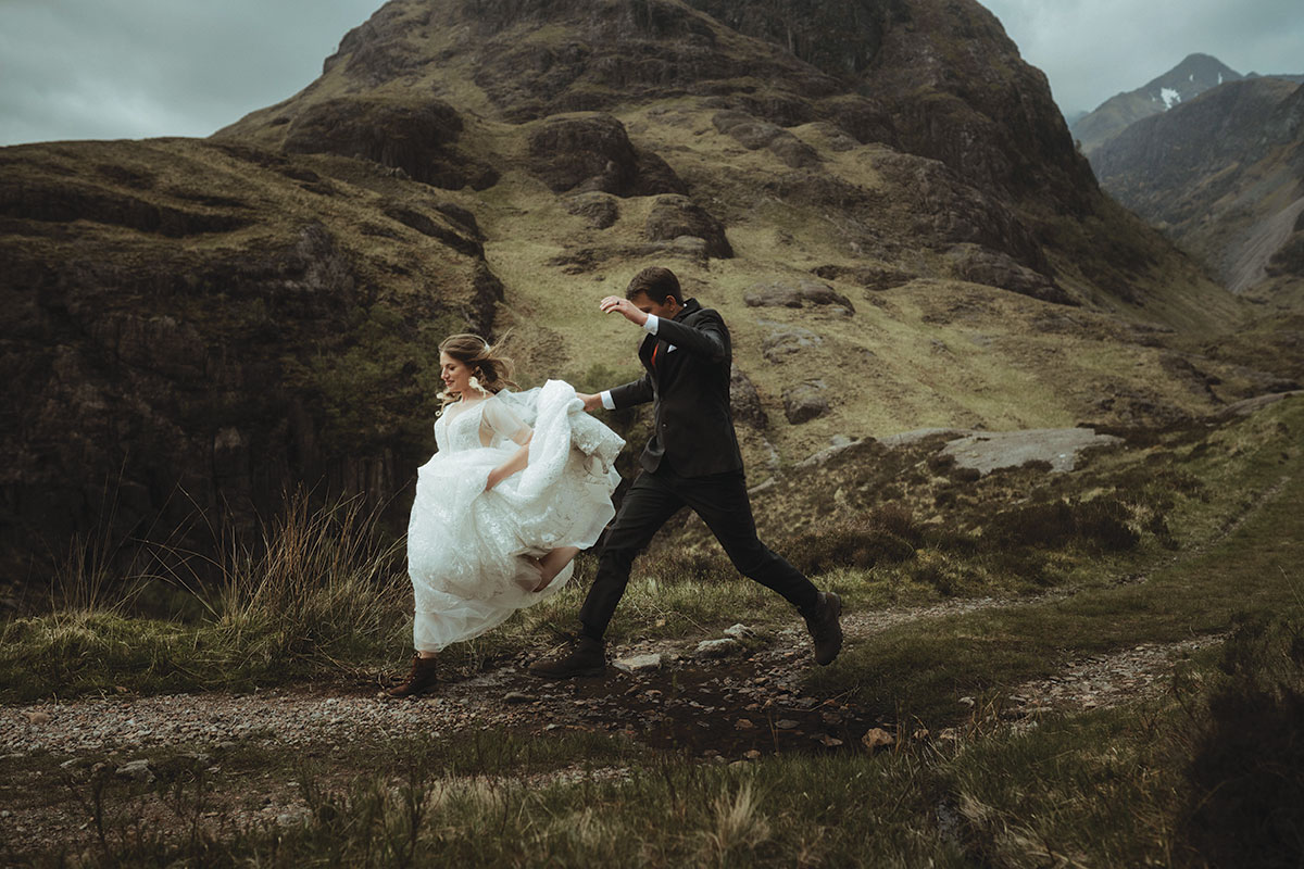 bride and groom run through the woods in the scottish highlands on their wedding day