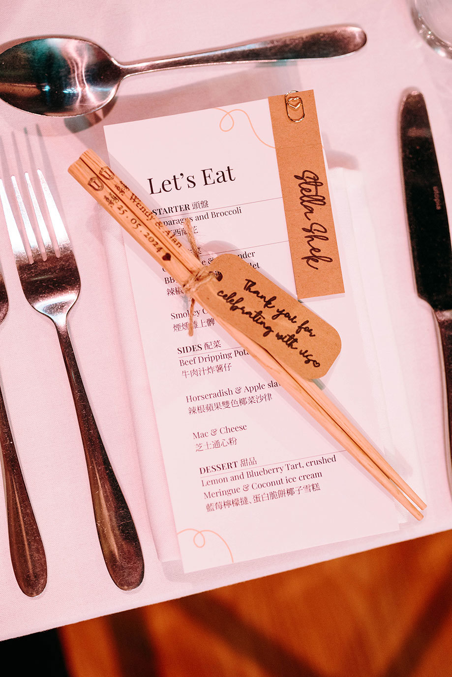 a close up of a wedding menu on a table with personalised chopsticks and cutlery