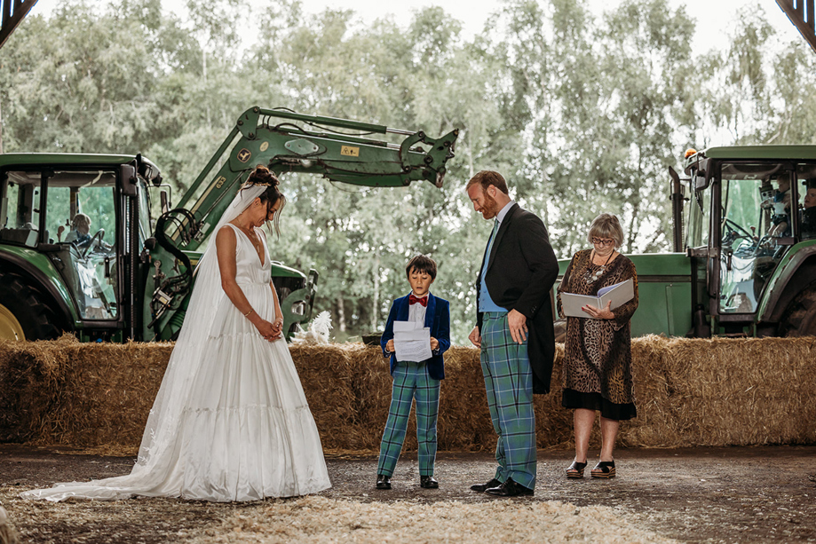 people Standing In Front Of Hay Bales At A Wedding Ceremony In A Farm Shed on Boswells Estate 