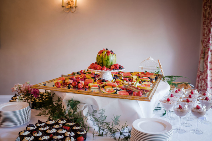 A Platter Of Fruit, Chocolate Mousse In Glasses And Cupcakes On A Dining Table