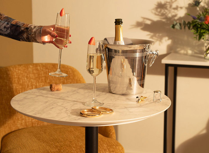 Table set up with prosecco flutes and ice bucket with hand holding glass