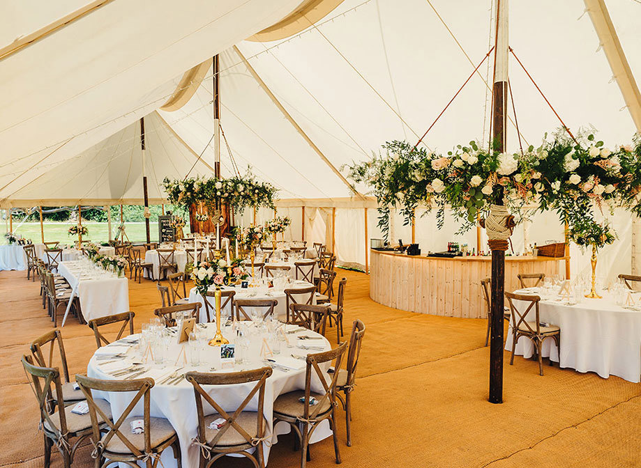 The marquee set up for a wedding reception including flowers and round tables