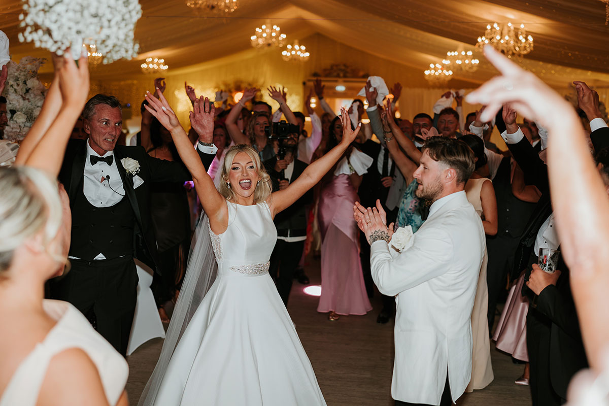 Bride celebrating on packed dancefloor during evening reception at Ingliston Country Club wedding