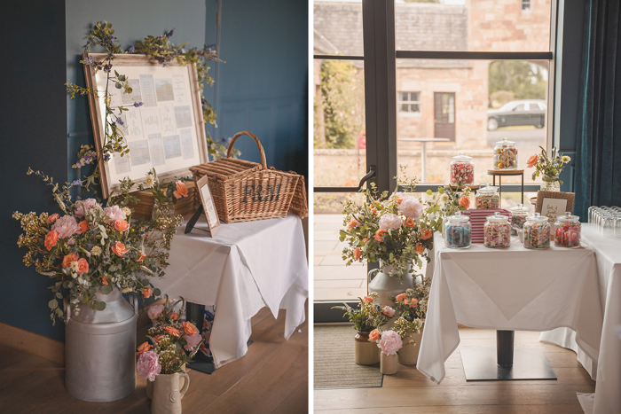 Bunches of orange and pink flowers on the floor next to a seating chart display and a table full of glass jars of sweets